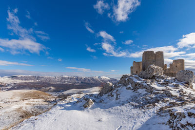 Snow covered buildings against blue sky