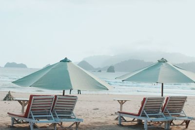 Chairs on beach against clear sky