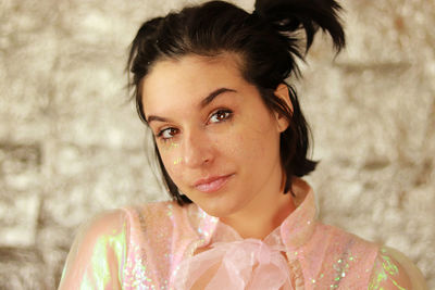 Close-up of young woman looking into the camera with glitter