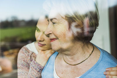 Young woman and senior woman behind windowpane