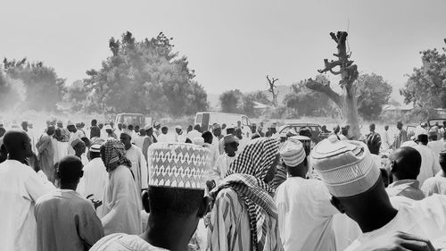 Crowd standing on field against trees during traditional festival