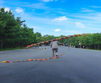 Rear view of man performing on street against sky