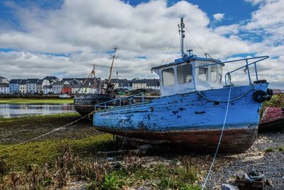 Fishing boats moored at harbor against sky