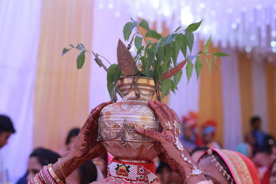 Cropped hands of woman carrying container on head during wedding ceremony