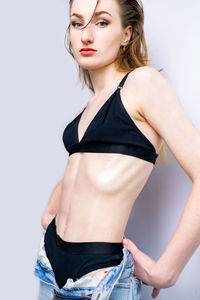 Portrait of young woman standing against white background