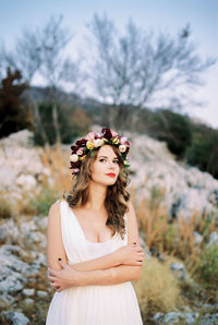 Portrait of smiling young woman standing against trees