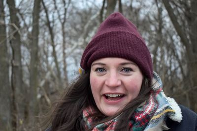 Portrait of happy young woman against trees