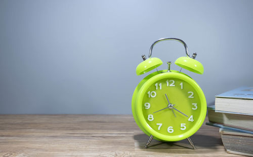 Close-up of clock on table against wall