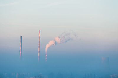 Smoke emitting from factory against clear sky