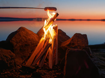 Food on stick over bonfire during sunset
