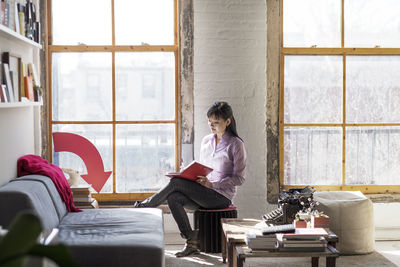 Businesswoman writing in book while sitting in creative office