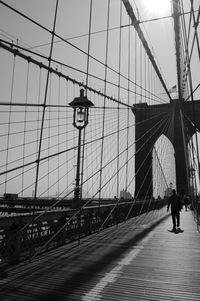Man walking on brooklyn bridge against sky