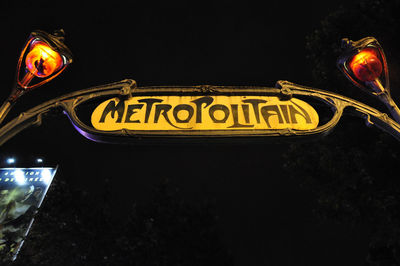 Low angle view of illuminated sign against clear sky at night
