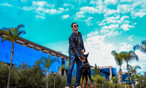 Man standing with dog in city against blue sky