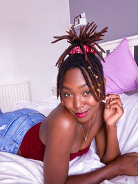 Portrait of young woman sitting on bed at home