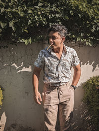 Portrait of young man standing against wall