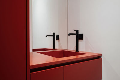 A bathroom with red cabinetry, a sink, and a mirror