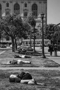People lying down on grass at park in city