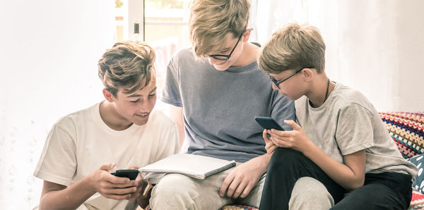 Side view of man using phone while sitting at home