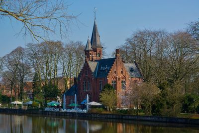 Brugge canal amidst trees and buildings against sky