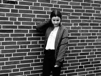 Young woman standing against brick wall