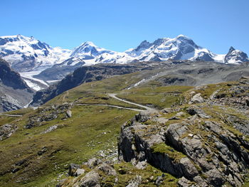 Tourist,backpacker, hiking on the mountain trial with view of snowcapped mountains against sky