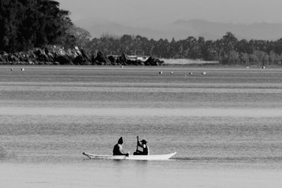 Two people sailing in boat at lake 