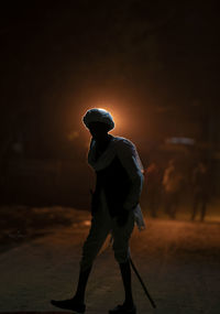 Rear view of silhouette man walking on field at night