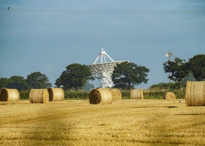 Hay bales on landscape against clear sky