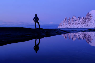 Silhouette man standing by sea against sky