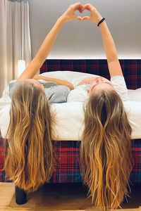 Rear view of young women relaxing on bed at home