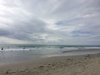 Scenic view of beach against cloudy sky