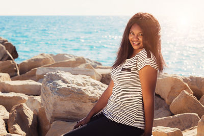 Young woman sitting on rock at beach