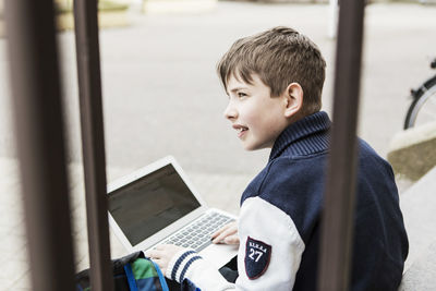 Schoolboy using laptop on steps