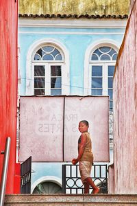 Side view of young man standing against building