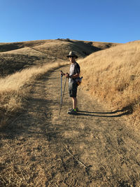 Side view of man standing on mountain against clear sky