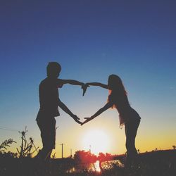 Silhouette couple standing against clear sky during sunset