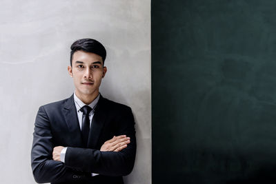 Portrait of young man standing against wall