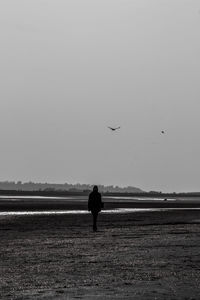 Silhouette woman standing on beach against sky