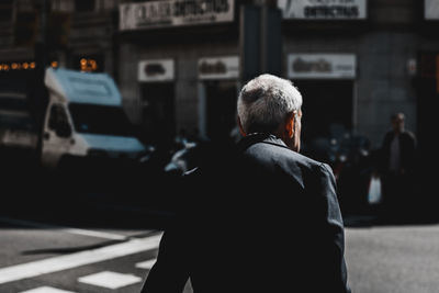 Rear view of man standing on street in city