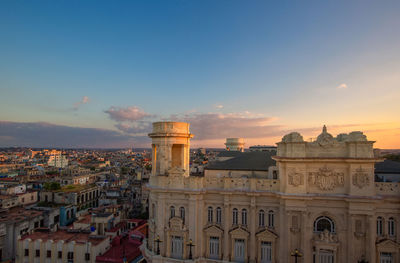 Buildings in town against sky during sunset