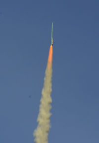 Low angle view of rocket launch against blue sky