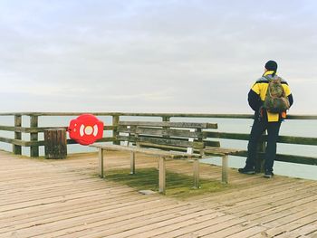 Man hiker with backpack on wet mole above sea. misty morning with smooth water level. vignetting 