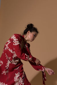 Side view of young woman standing against gray background