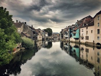 Buildings by river against sky in city