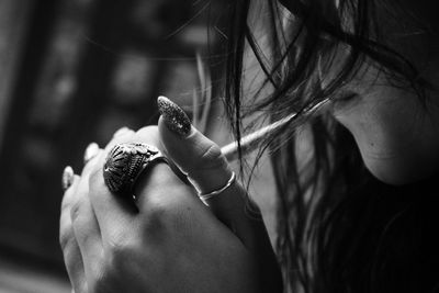 Cropped image of woman wearing ring smoking cigarette
