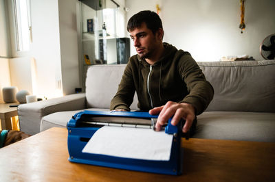 Young man using mobile phone while sitting on table