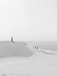 People on sand dune against sky