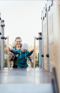 A boy, person with down syndrome walks in the park with his mother, spinning on the carousel