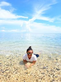 Young woman on beach against sky